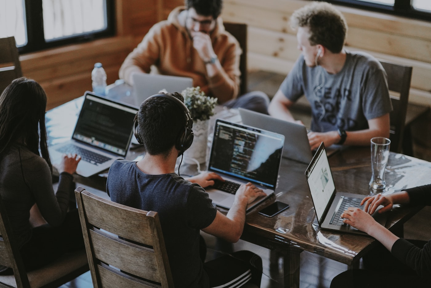 A group of people working on laptops around a large wooden table